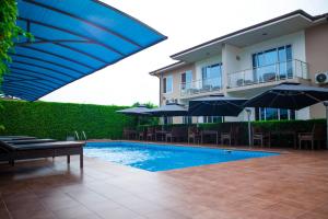 a swimming pool with chairs and umbrellas next to a building at Cromer Apartment Hotel in Accra