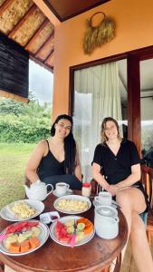 zwei Frauen sitzen an einem Tisch mit Essen drauf in der Unterkunft Papahan Bali in Sidemen
