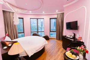 a pink hotel room with a bed and a television at A&D Luxury Hotel in Hanoi