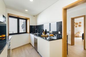 a kitchen with white walls and a large window at Casa de Arouca - Arouca Suítes in Arouca