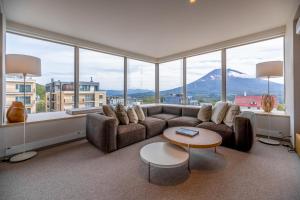 a living room with a couch and large windows at The Maples Niseko in Kutchan