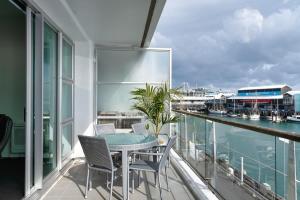 balcón con mesa, sillas y vistas al agua en Spacious Executive Apartmt,great Views! Location en Auckland