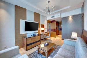 a living room with a couch and a flat screen tv at Metropolitain Dubai Hotel - Junior Suite - UAE in Dubai