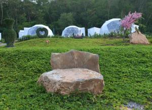 una silla de roca sentada en un campo con tiendas de campaña en NiNo San Glamping - Pak Chong, en Pak Chong