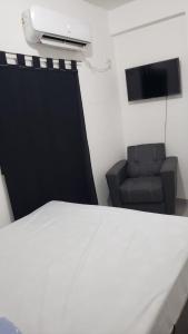 Cette chambre comprend un lit, une chaise et une télévision. dans l'établissement Apart Hotel - Eucaliptal, à Corrientes