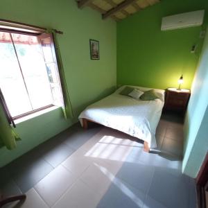 Dormitorio verde con cama y ventana en Solar de Campo en Villa Elisa