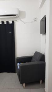sala de estar con sofá negro y TV en Apart Hotel - Eucaliptal en Corrientes