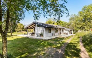 a small white cottage in a field with trees at Gorgeous Home In Strandby With Kitchen in Strandby