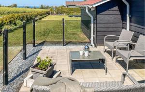 een patio met een tafel en stoelen en een tuin bij 3 Bedroom Amazing Home In Bogense in Bogense