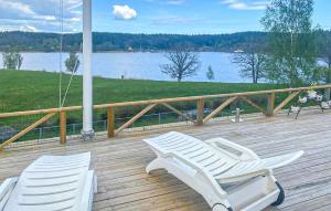 two white chairs sitting on a deck with a lake at Amazing Home In Valdemarsvik With Wifi in Valdemarsvik