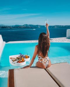 une petite fille assise dans une piscine avec une assiette de nourriture dans l'établissement Phos The Boutique, à Akrotiri