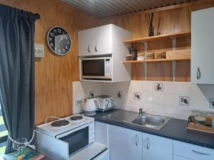 una pequeña cocina con fregadero y microondas en Crinkly Cottage en Te Kuiti