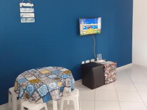 a room with a bed and a tv on a blue wall at Apartamento 101 com vista da piscina e mar in Piúma