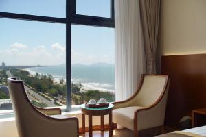 a hotel room with two chairs and a large window at Victory Hotel Vung Tau in Vung Tau