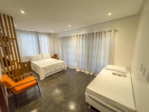 a bedroom with two beds and a chair and a window at Casa Aconchego - Barreirinhas in Barreirinhas
