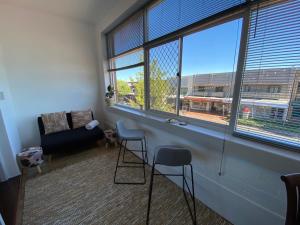 a living room with two chairs and a couch and windows at Stay on Summer - CBD Apartment in Orange