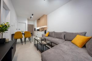 a living room with a gray couch and yellow pillows at Miodowy apartament z dużym tarasem w Rewalu, blisko morza in Rewal