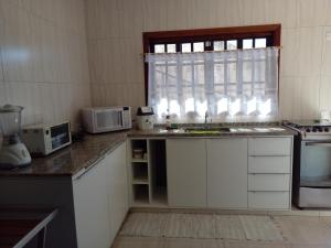 a kitchen with a sink and a microwave and a window at Casa dos Neves in Campos do Jordão