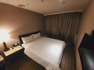 Pokój hotelowy z białym łóżkiem i oknem w obiekcie Well Garden Hotel w mieście Taoyuan