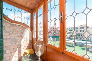 un verre de vin assis sur une table devant une fenêtre dans l'établissement Rialto Terrace on the Grand Canal, à Venise