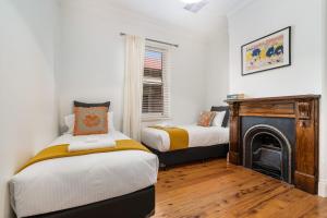 a bedroom with two beds and a fireplace at Ambrose On Byng - Central Location in Orange
