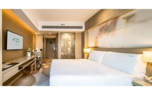 1 dormitorio con 1 cama blanca grande y escritorio en Holiday Inn Kunming City Centre, an IHG Hotel en Kunming