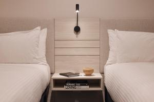 a bedroom with two beds and a table with a vase on it at Rydges Darling Square Apartment Hotel in Sydney +33 photos