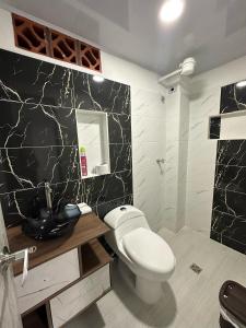 a bathroom with a white toilet and a black marble wall at Hotel Las Vegas in Guatapé