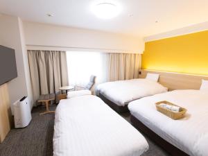 富山市にある富山地鉄ホテルの黄色の壁のホテルルーム(ベッド2台付)