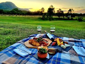 eine Picknickdecke mit einem Teller Essen und Gläsern Wein in der Unterkunft Leogate Estate Villas in Pokolbin