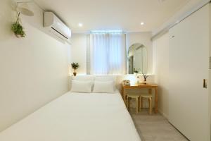 a white bedroom with a bed and a table at Hotel Rawa in Seoul