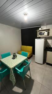 La cuisine est équipée d'une table, de chaises et d'un réfrigérateur. dans l'établissement Quitinete ótima localização, à Foz do Iguaçu
