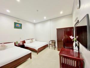 a hotel room with two beds and a table and a desk at Du Hung 2 Hotel in Hà Tiên