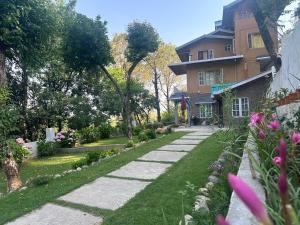 a garden with a walkway next to a building at Kut House in Pālampur