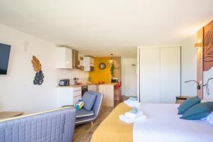 a room with a bed and a couch and a kitchen at Studio neuf et cosy proche des plages - L'Alamanda in Le Gosier