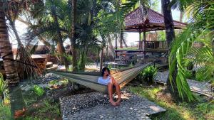 a woman sitting in a hammock in a resort at Villa Selina in Tejakula