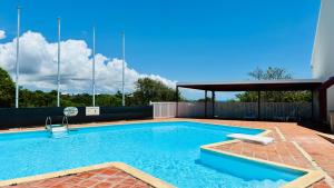 a large swimming pool with a brick patio and a pavilion at Studio neuf et cosy proche des plages - L'Alamanda in Le Gosier