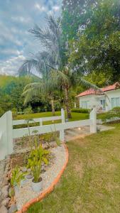 una cerca blanca frente a una casa con una palmera en The Hawk's Nest Resort, en Sabang