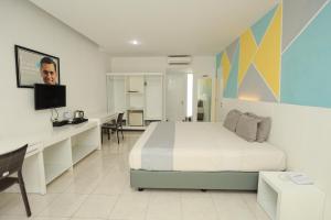 a bedroom with a bed and a desk and a tv at LPP Convention Hotel Demangan in Yogyakarta