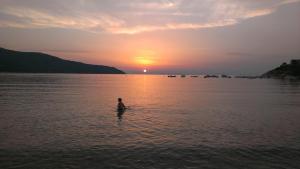 Un uomo in piedi in acqua al tramonto di Marina VIP a Marciana