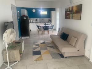 un soggiorno con divano e tavolo e una cucina di F3 dans maison individuelle avec jardin arboré a Le Lamentin