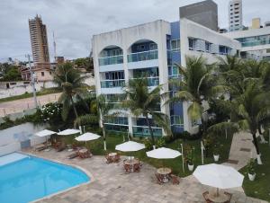 a hotel with a pool and tables and umbrellas at FLAT PONTA NEGRA BEACH-Natal in Natal