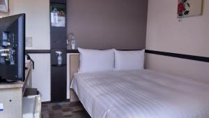 a bedroom with a bed with white sheets and a television at Toyoko Inn Tokyo Otsuka-eki Kita-guchi No 1 in Tokyo