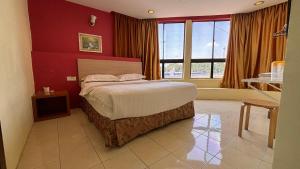 a bedroom with a bed and a red wall at Hotel Centum in Klang