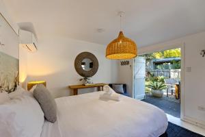 1 dormitorio con cama blanca y espejo en The Cottage at Pearl Beach, en Pearl Beach