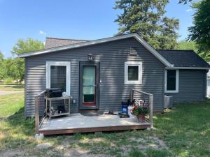 Una pequeña casa gris con un porche y una terraza. en Creekside cottage, en Owatonna