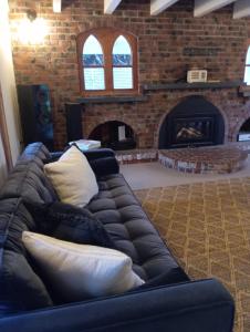 a black leather couch in a living room with a fireplace at Kingsdown Manor B&B Timaru in Timaru