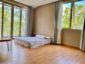 a bedroom with a bed in a room with windows at Green villa in Bien Hoa