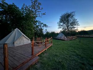 two tents in a field with a wooden deck at Deleni Retreat - Glamping in Buzău