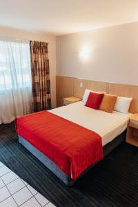 a hotel room with a large bed with a red blanket at The Mayfair Ridge Hotel in Emerald